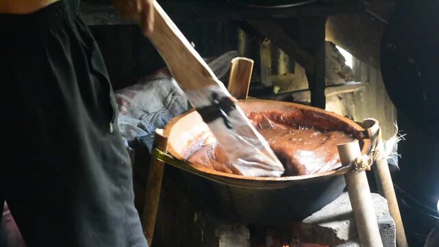 Making dodol in a large container, also called kalu dodol in sri lanka, dark sweet candy, made from coconut milk, jaggery and rice flour, sticky, thick, sweet toffee, closeup