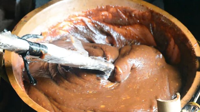 Making dodol in a large container, also called kalu dodol in sri lanka, dark sweet candy, made from coconut milk, jaggery and rice flour, sticky, thick, sweet toffee, closeup