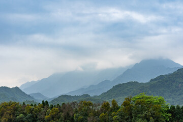 Dujiangyan mountains shrouded in mist under a cloudy sky.