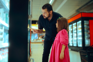 Father and Daughter Shopping at the Grocery Store. Dad shows little girl frozen products in the...