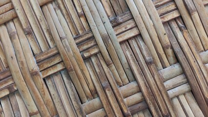 Close-up photo of a traditional woven bamboo texture with natural rustic colors and unique handmade patterns. This image is ideal for use in backgrounds, graphic design