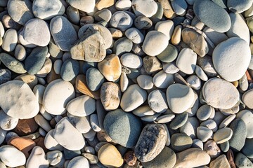 A close-up view of a pile of smooth beach stones, showcasing natural colors and textures. The...