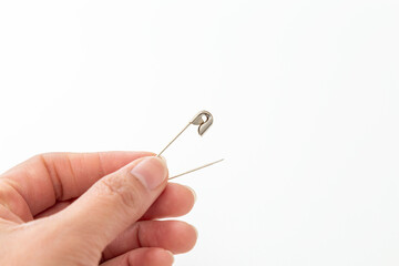 安全ピンを持つ手元　白バック