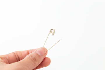 安全ピンを持つ手元　白バック