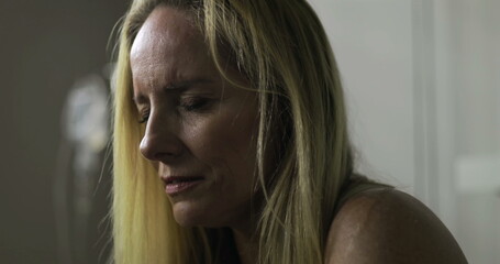 Woman sitting quietly in medical room with eyes closed, processing difficult emotions alone during...