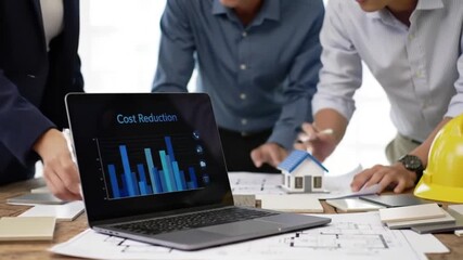 Cost Reduction Data Presentation with Charts on Laptop and Team Collaboration