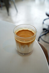 Close up glass of Dirty Latte coffee on white table