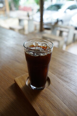 Close up glass of iced black coffee on wooden table