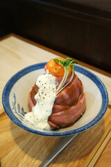 Close up bowl of sous vide beef with raw yolk and white sauce