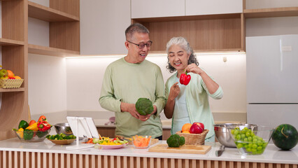 Asian older couple healthy cooking prepares fresh vegetables for nutritious meal in modern home kitchen following online recipe happy lifestyle
