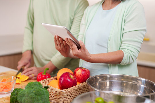 Asian adult couple preparing healthy meal in modern kitchen using digital tablet for recipe instruction senior lifestyle cooking fresh food at home - Powered by Adobe