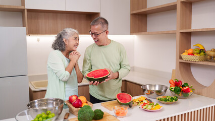 Asian older adults preparing healthy meal together modern kitchen enjoying fresh fruit vegetables for wellbeing happy lifestyle promoting healthy eating domestic life