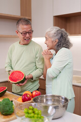 Older Asian couple preparing fresh fruit watermelon kitchen healthy lifestyle cooking happy senior...