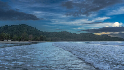 Morning seascape. The ocean waves roll towards the shore, foam, and spread across the beach. Sun...