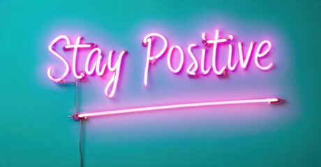 Bright pink neon sign displays Stay Positive against teal wall. Simple message, uplifting vibe, modern aesthetic. Minimalist design.