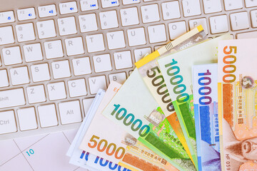 South Korean won money bills currency notes spread across keyboard, symbolizing online banking financial activities