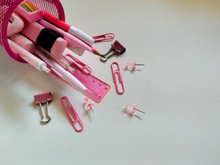 pink school supplies are arranged on a white table