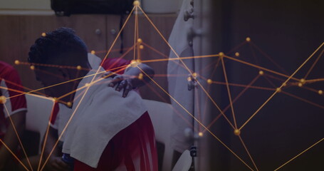 Sitting athlete in jersey draping towel, teammate offering hand in locker room with network overlay