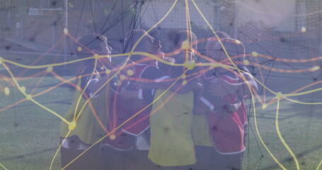 Huddling nine boys wearing colorful training bibs on soccer turf with network graph overlay