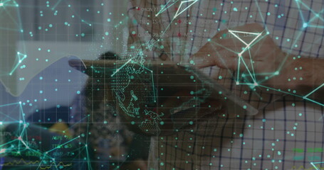 Mid adult man holding tablet computer and exploring holographic network in tech lab, with circuits