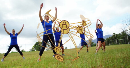 Six adults wearing blue tops black pants stretching on grassy field, with golden orb and goalposts