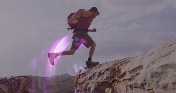 Leaping adult male hiker navigating desert canyon ridge, with daypack backpack and hiking boots