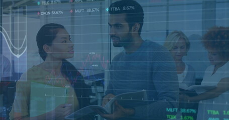 Professionals in business attire reviewing stock data on tablet and binder in office, with charts