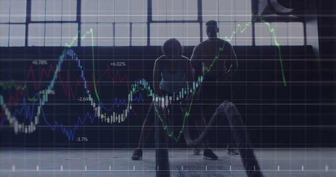 Workout partners performing battle rope gripping ropes in gym with concrete floor and graph overlay