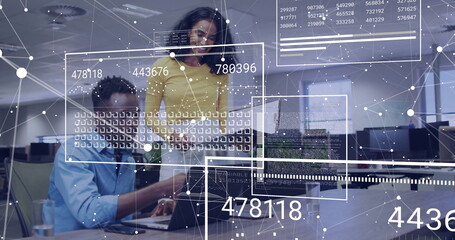 Collaborating technology experts examining network data overlays on laptop in open-plan office