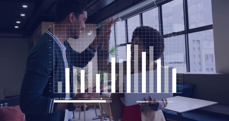 High-fiving two business professionals in office lounge, with tablet and digital bar chart overlay