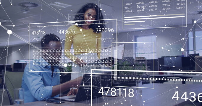 Collaborating technology experts examining network data overlays on laptop in open-plan office