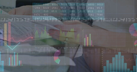 Studying woman in blazer reviewing financial reports at office desk, with digital chart overlays