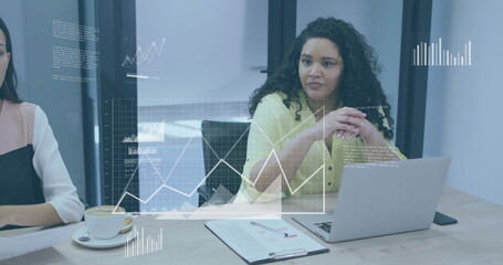 Analyzing floating data charts woman in yellow blouse typing on silver laptop in conference room