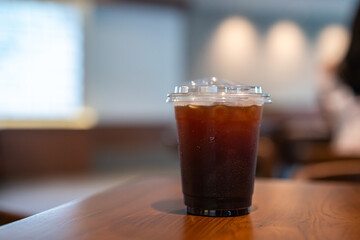 Close-up of Americano ice coffee or black coffee in cup mug on  wood desk office desk in coffee shop at the cafe in garden,during business work concept