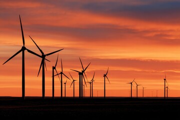 Silhouette of wind turbines against orange and blue sunset sky, green energy technology and sustainable power generation with renewable resources.