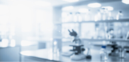 Obraz premium Blurred laboratory interior with microscope and glassware on shelves in a bright setting, reflecting professional scientific atmosphere with modern clean research design.