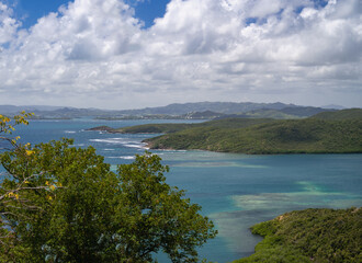 Breathtaking coastal view with serene waters and lush greenery under clouds.