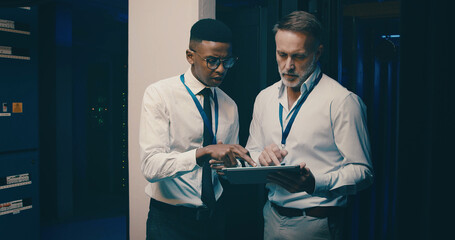Talking, inspection and men in server room on tablet for network solution, IT support and cybersecurity. Manager, discussion and people on digital tech for database, programming and hardware update