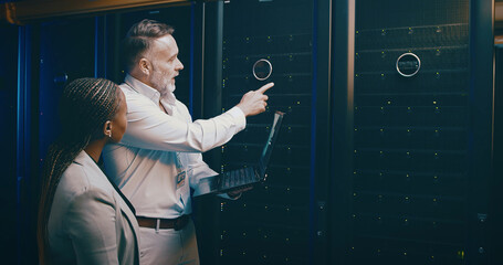 People, cyber security and laptop in server room, pointing and programming with teamwork. IT...