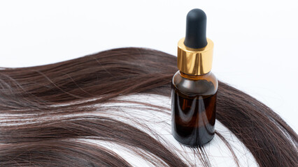 Hair treatment oil bottle placed beside smooth, shiny hair strands, showcasing effective split ends...