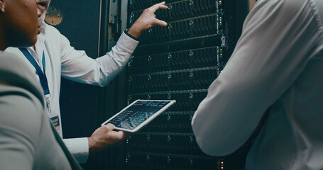 Tablet screen, hand and discussion in server room for code or system performance. People,...