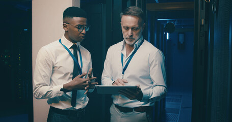Talking, server room and men on tablet for network solution, IT support and cybersecurity....