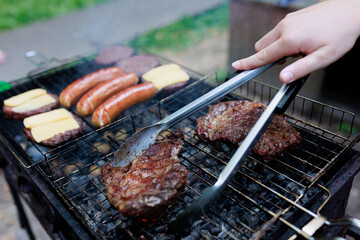 steaks are grilled and shot with selective focus, with hamburger patties and sausages being...