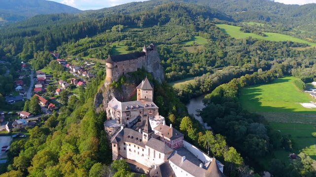 Aerial view of the Orava castle at sunset in Slovakia. Medieval Oravsky Hrad castle on high and steep cliffs by the Orava River. Beautiful evening drone footage. Medieval fortress in golden light