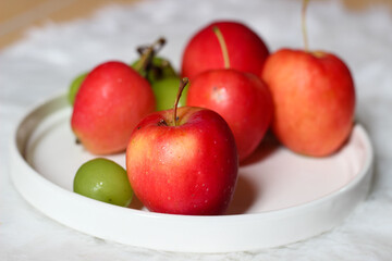 Fresh red apples and palm fruits on a white plate. Organic tropical fruits perfect for healthy eating, nutrition, and food photography.