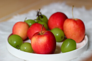 Fresh red apples and palm fruits on a white plate. Organic tropical fruits perfect for healthy eating, nutrition, and food photography.