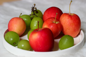 Fresh red apples and palm fruits on a white plate. Organic tropical fruits perfect for healthy eating, nutrition, and food photography.