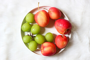 Fresh red apples and palm fruits on a white plate. Organic tropical fruits perfect for healthy eating, nutrition, and food photography.