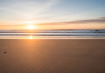 Fototapeta premium The sun rises over the ocean, casting a golden glow on the beach.