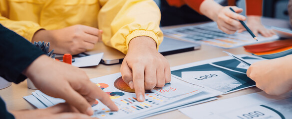A dynamic team engages in a collaborative brainstorming session at a modern workspace, examining colorful charts and discussing business strategies. SACTR